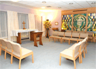 Inside the hospital chapel, chairs arranged to face the table at the back of the room