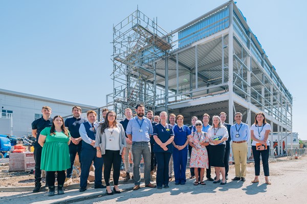 WVT clinicians and staff involved in the new unit are pictured with building contractor representatives in front of the steel skeleton of the new facility